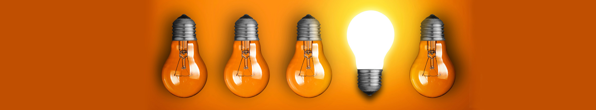 Five light bulbs are in a row on an orange background. The fourth light bulb in the row stands out from the others because it is facing upwards and is lit up, where as the others are all facing down and are not lit up. This symbolises the way that Security Alarm Monitoring stand out from the other business that provide wholesale alarm monitoring.
