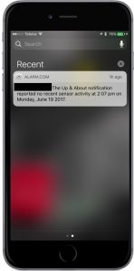 A black iPhone with a notification from Ageing In Place powered by Alarm.com